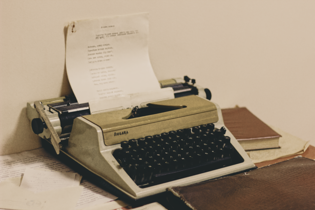 Vintage typewriter with paper and books, symbolising the What is New In Italy monthly subscription